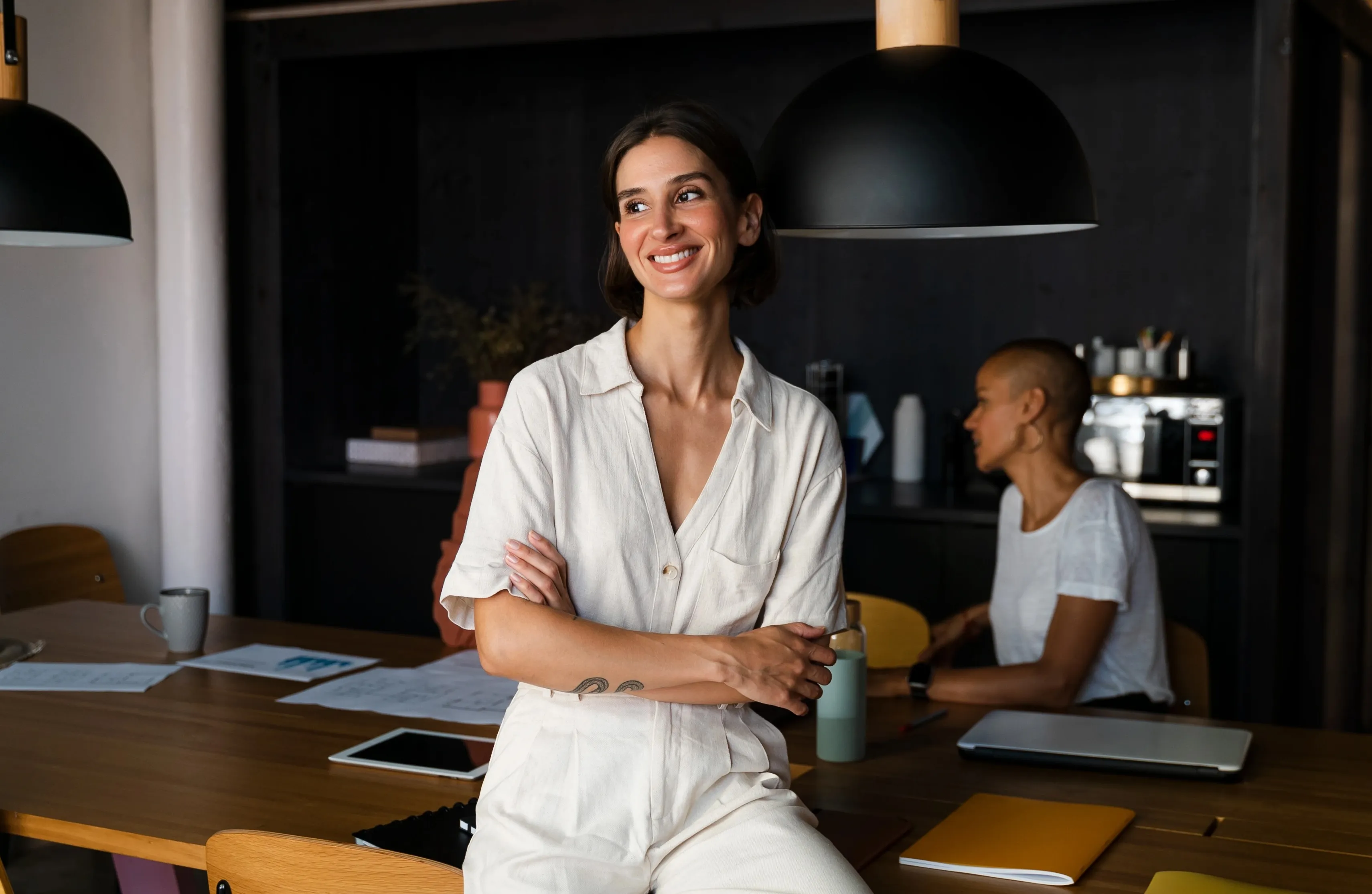 A woman standing in front of a wooden table.