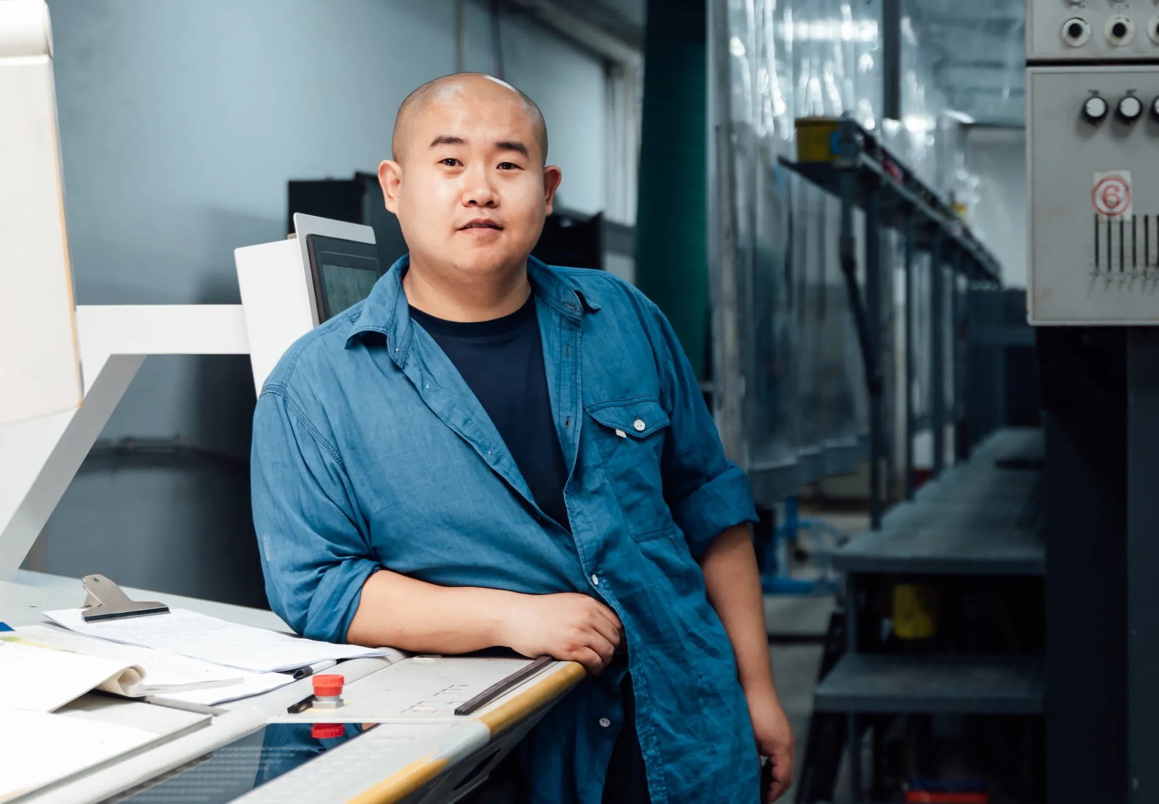 A man standing in front of a machine in a factory.