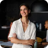 A woman standing with her arms crossed smiling.