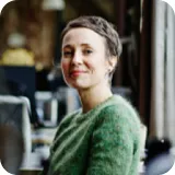 A woman in a green sweater smiles at the camera.