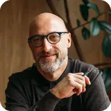 A man with glasses is holding a pen.