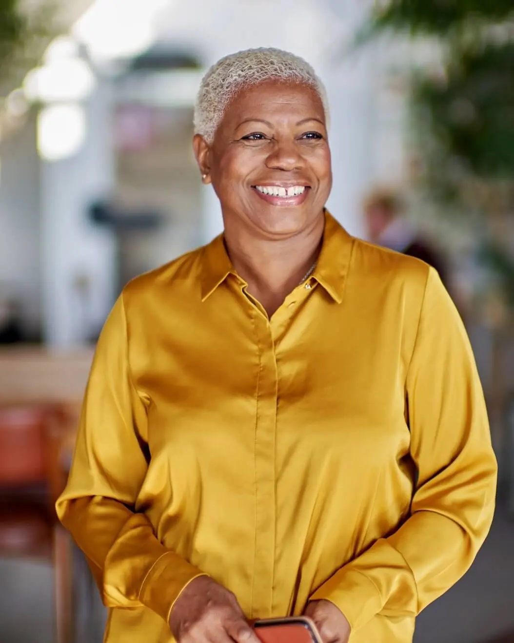 A woman in a yellow shirt is smiling.