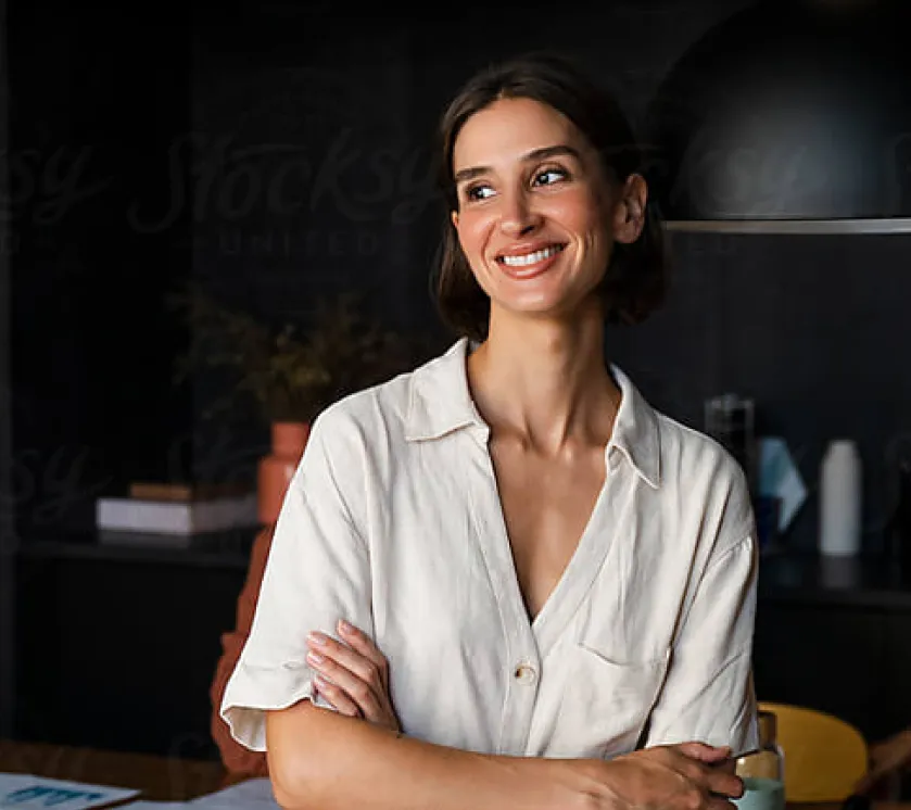 A woman standing with her arms crossed smiling.